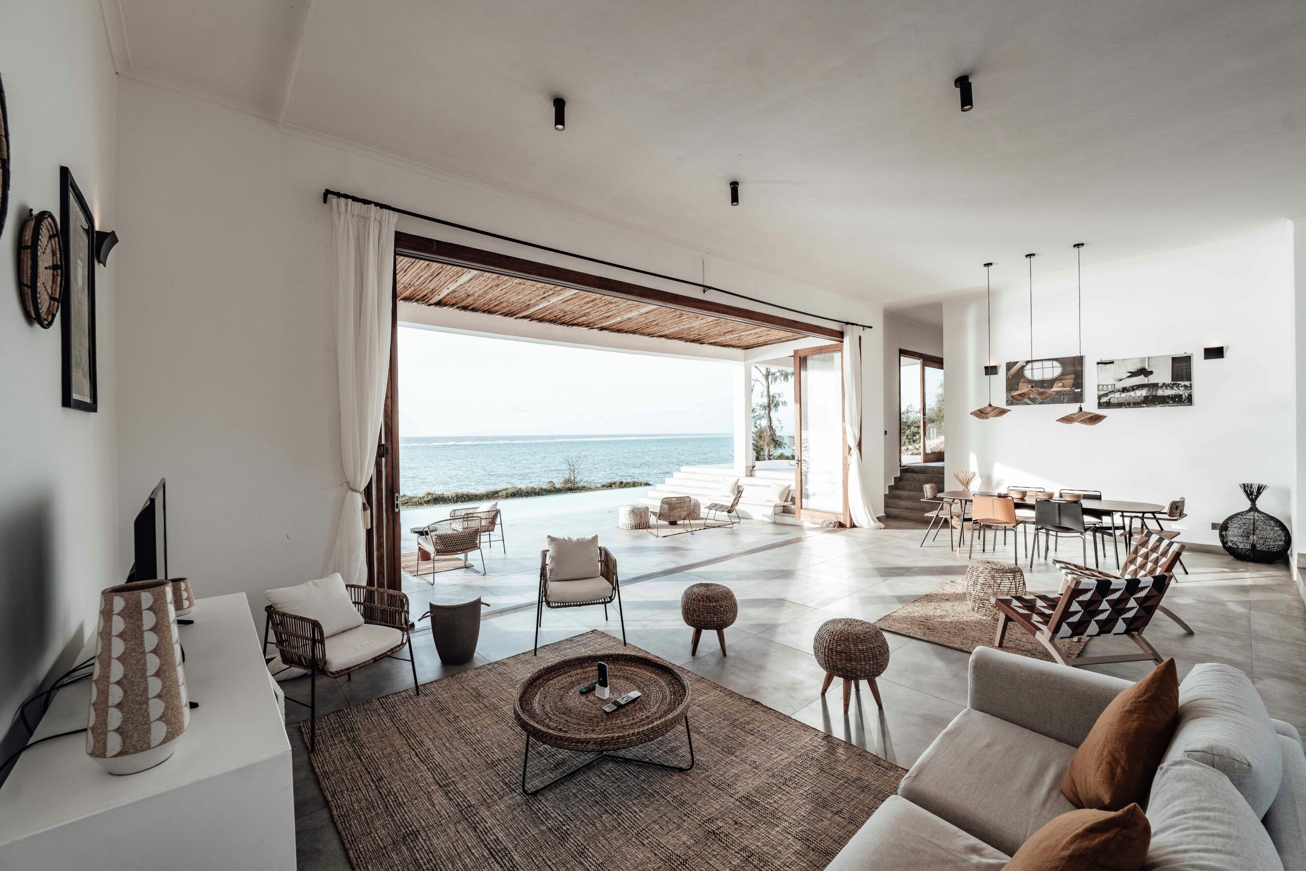 A spacious, minimalistic living room with a stunning ocean view, showcasing modern interior design.